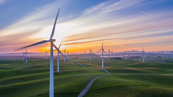 Several wind turbines set in a field at sunset