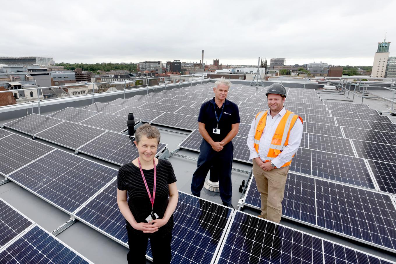Equans employees stood on Newcastle Central Library roof next to roof top solar
