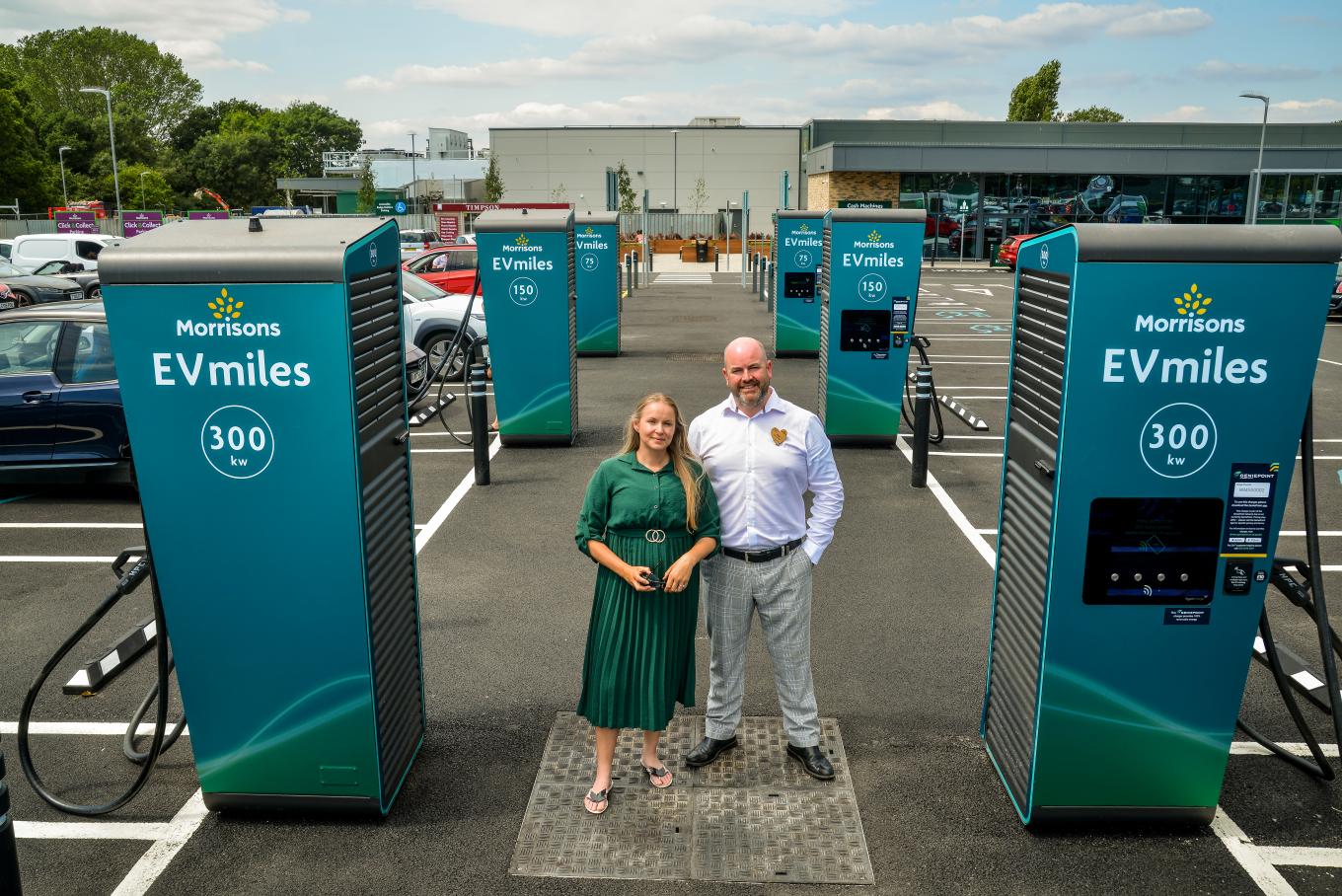Dee Humphries and Paul Tracey standing next to EV chargers in Morrisons car park