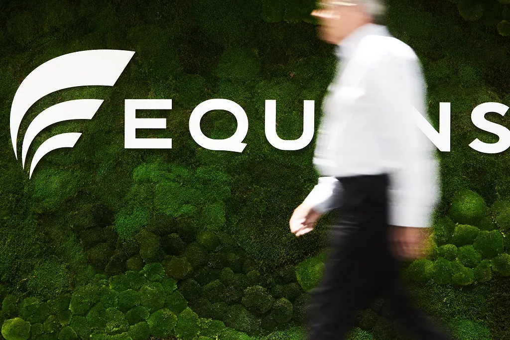 A gentleman walking past an Equans entrance sign