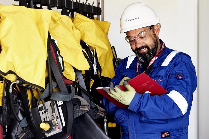 Nuclear industry employee writing in book next to safety equipment