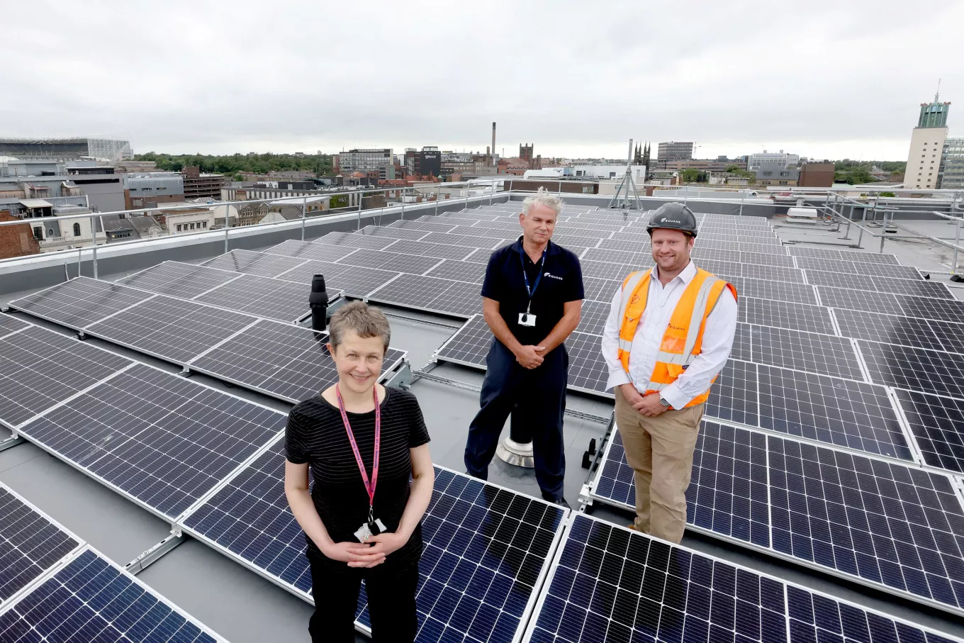 Equans employees stood on Newcastle Central Library roof next to roof top solar
