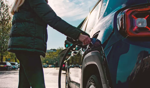 person charging black EV car with Genie Point charger
