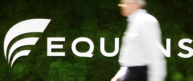 A gentleman walking past an Equans sign