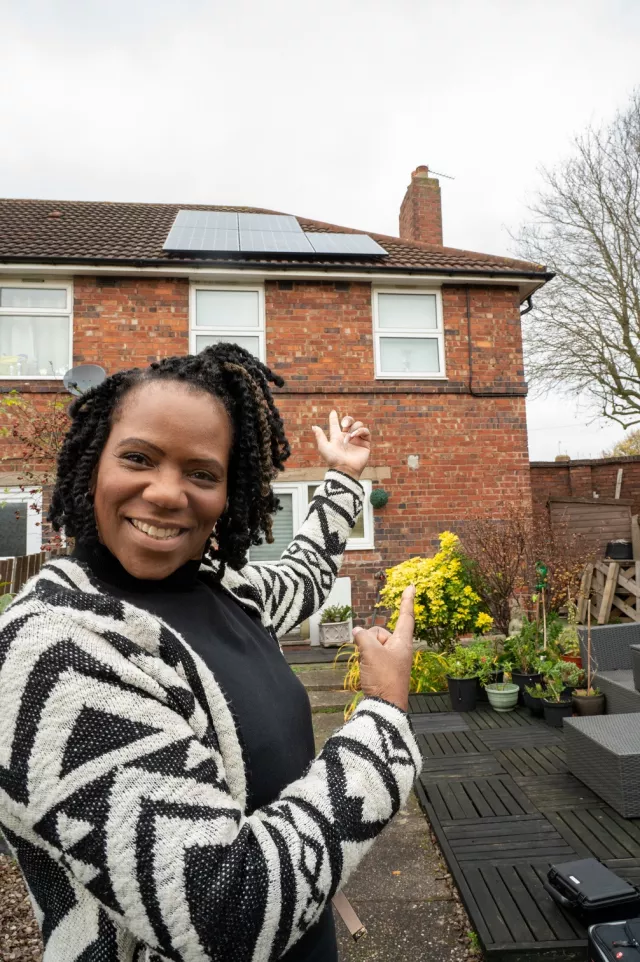 A lady standing in front of a house with solar panels in Erdington