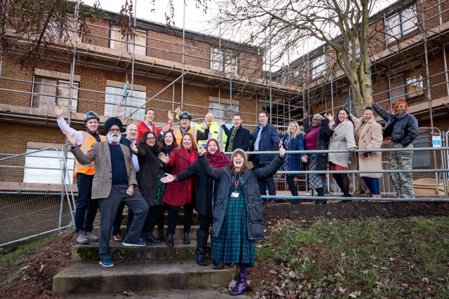 Staff from Equans and St Basil's celebrating the start of work in front of scaffolding