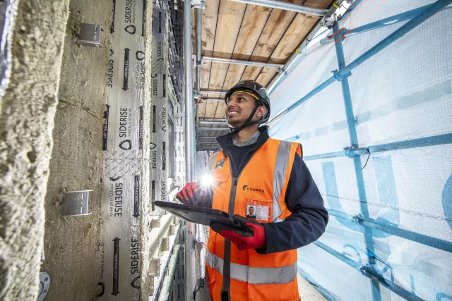 Equans employee surrounded by scaffolding and undertaking retrofit assessments