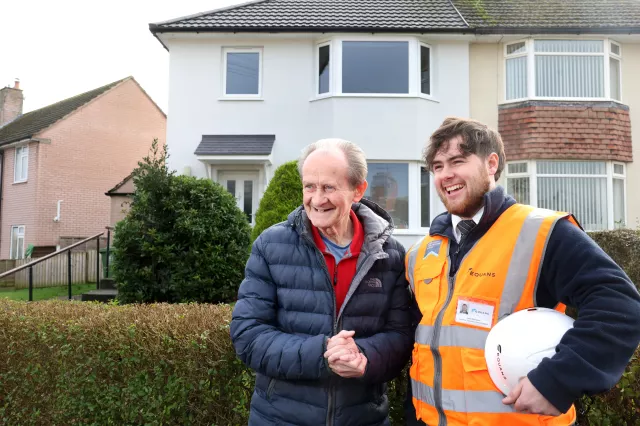 Image of an Equans employee shaking hands with a social housing resident outside his property - both smiling