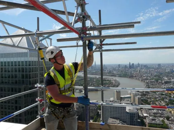 man in hard hat, high vis vest and protective glasses on scaffolding