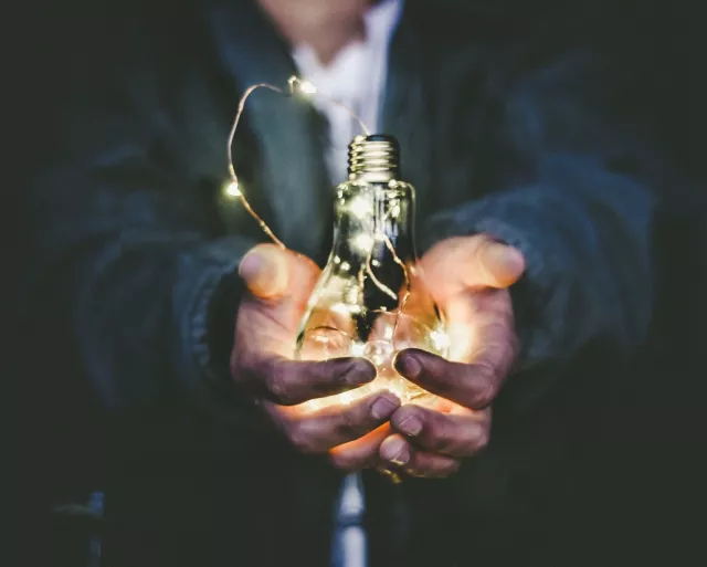 Man holding light bulb in hands with LED string lights in