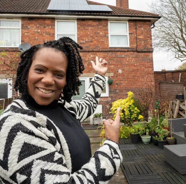 Image of lady standing in front of her house with solar panels at Erdington