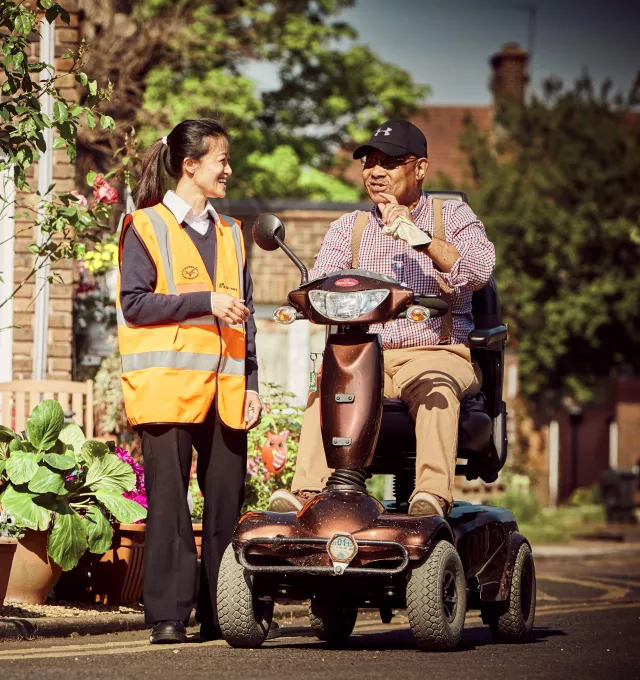 Equans employee supporting person in electric wheelchair