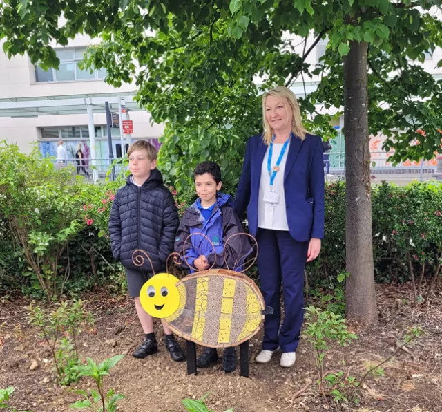 Children with statue of a bumble bee