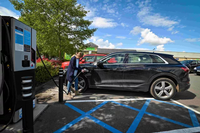 A lady charging her EV at a genie point charger in ASDA