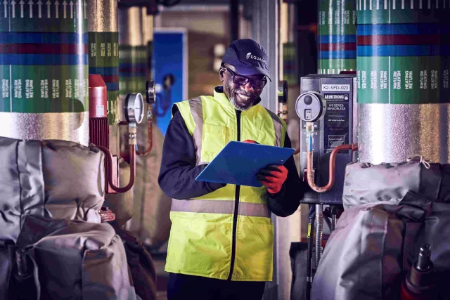 An Equans employee with clipboard in boiler room